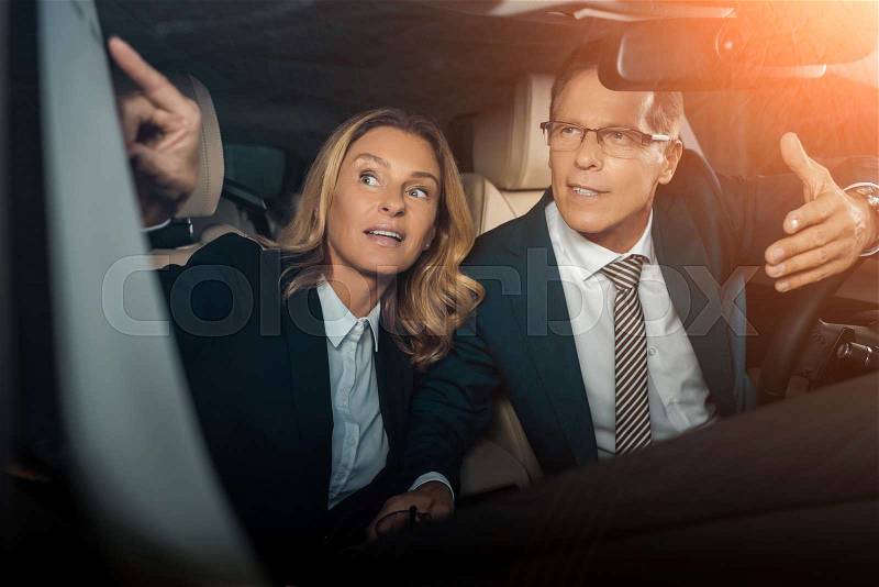 Business couple in formal wear checking new car, stock photo