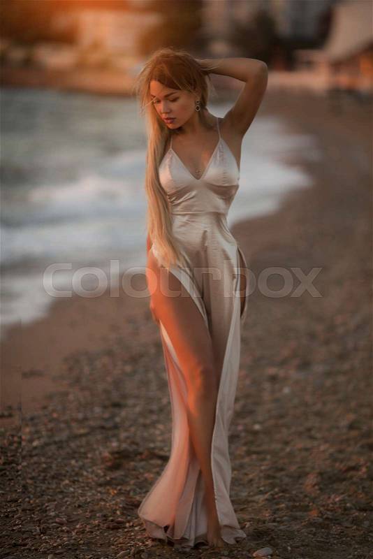 Beautiful young woman in long dress in the beach, stock photo