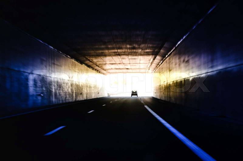 Car silhouette exiting dark tunnel - long exposure security and safety in dark unlighted area, stock photo