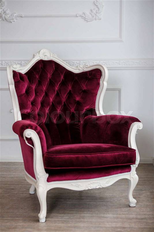 Red velour wood armchair in white room, stock photo