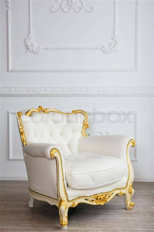 White leather wood armchair with golden decor in a white living room, stock photo