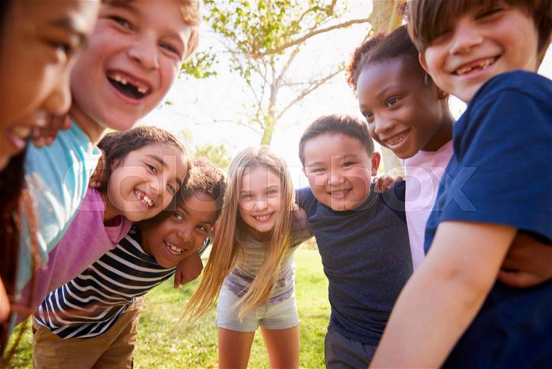 Multi-ethnic group of schoolchildren laughing and embracing, stock photo