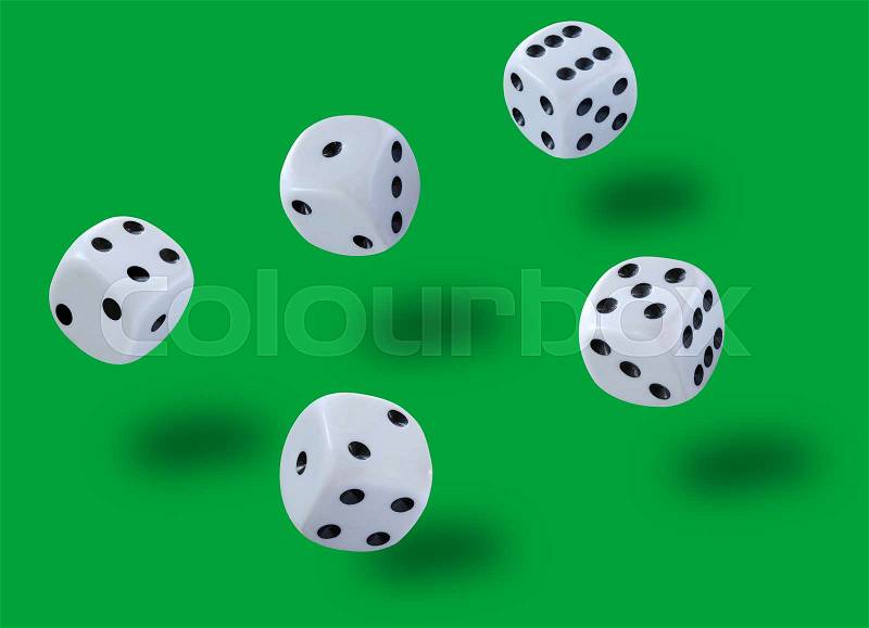 Five white dices thrown jump in a craps game, yatzee or any kind of dice game against a green background, stock photo
