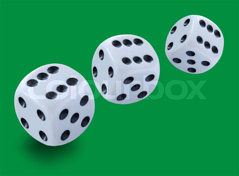 Three white dices of different size thrown in a craps game, yatzee or any kind of dice game against a green background , stock photo