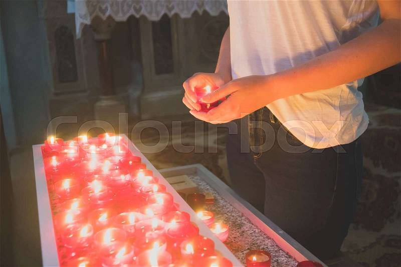 Woman holding candle near altar in church, stock photo