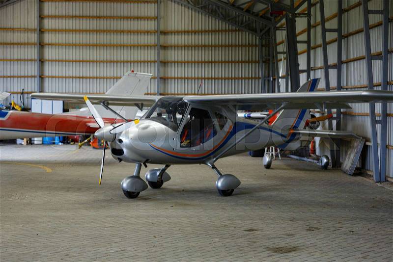 Small airplane standing in big hangar. copyspace, stock photo