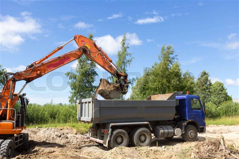 The excavator loads the tipper truck on construction site, stock photo