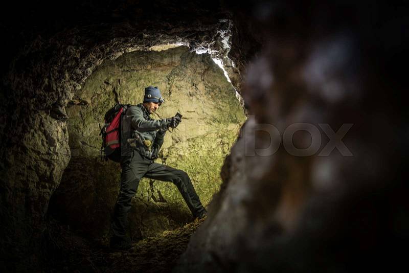 Deep Cave Exploration by Men with Flashlights and Backpack. Caucasian Caver in the Grotto, stock photo