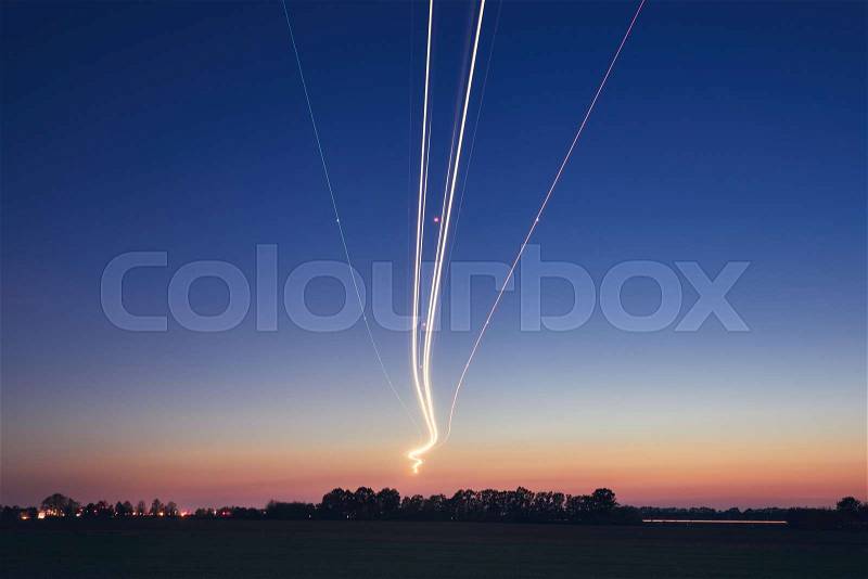 Light trails of airplane during landing at airport after sunset. Prague, Czech Republic, stock photo