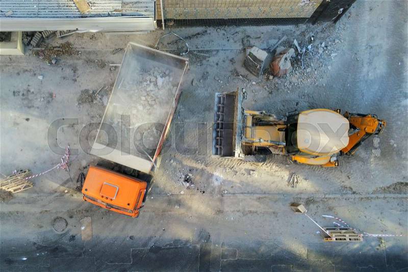 Bulldozer loader uploading waste and debris into dump truck at construction site. building dismantling and construction waste disposal service. Aerial drone ..., stock photo
