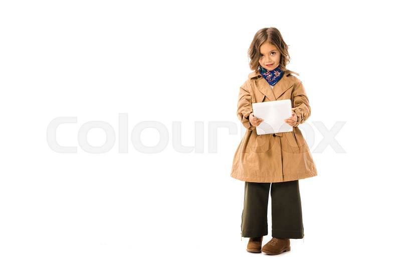Beautiful little child in trench coat using tablet and looking at camera isolated on white, stock photo