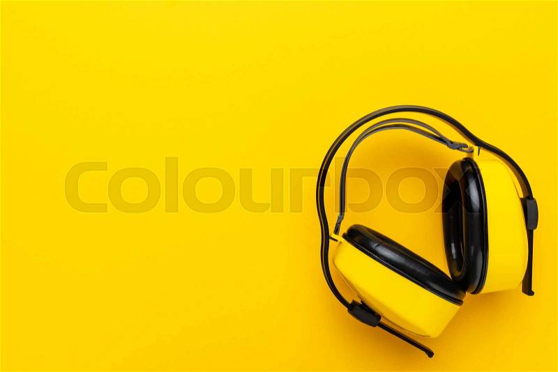 Hearing protection industrial ear muffs on yellow background. top view of yellow protective ear muffs with copy space, stock photo