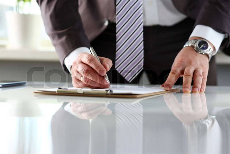 Male arm in suit and tie fill form clipped to pad with silver pen closeup. Sign gesture read pact sale agent bank job make note loan credit mortgage investment ..., stock photo