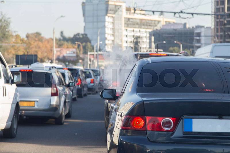 Vapour smoke go out from a car at a traffic jam. There are a lot of cars in the highway, stock photo