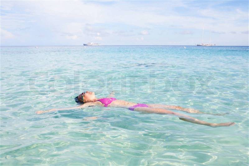 Woman Floating In Crystal Clear Water, stock photo