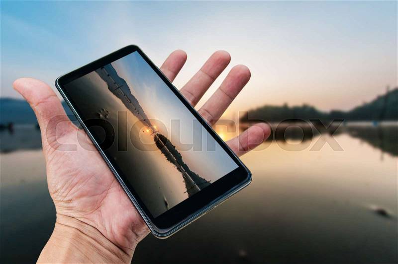 Hand holding smartphone landscape nature background, stock photo