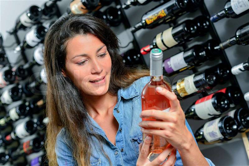 Lady tempted by bottle of rose wine, stock photo