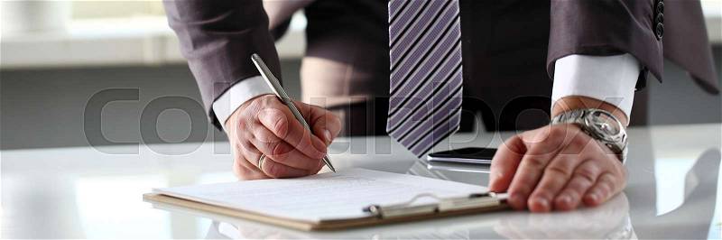Male arm in suit and tie fill form clipped to pad with silver pen closeup. Sign gesture read pact sale agent bank job make note loan credit mortgage investment ..., stock photo