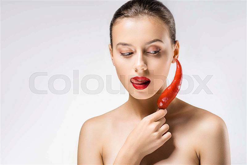 Young beautiful woman with red lips holding chili pepper and licking lips, stock photo