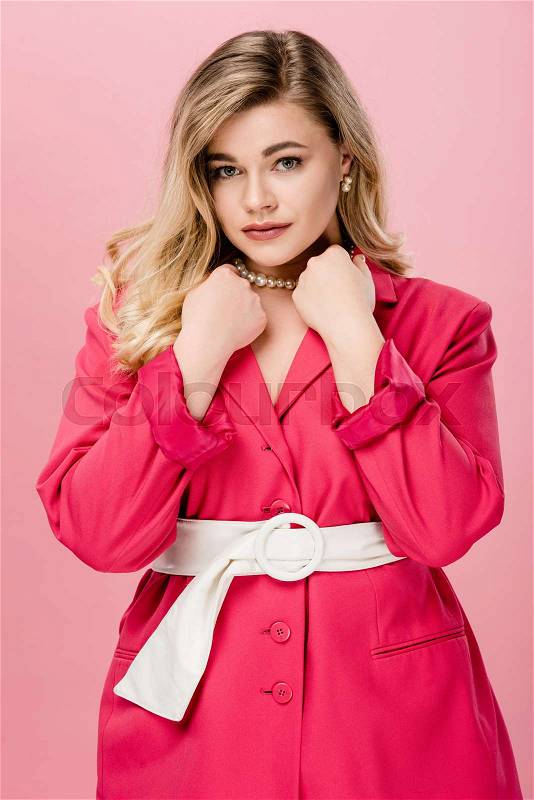 Elegant young woman in pink trench coat looking at camera isolated on pink , stock photo