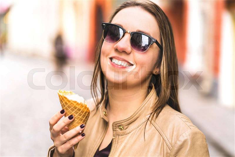 Ice cream on messy face. Happy laughing woman eating melting and dripping ice cream in the city, stock photo