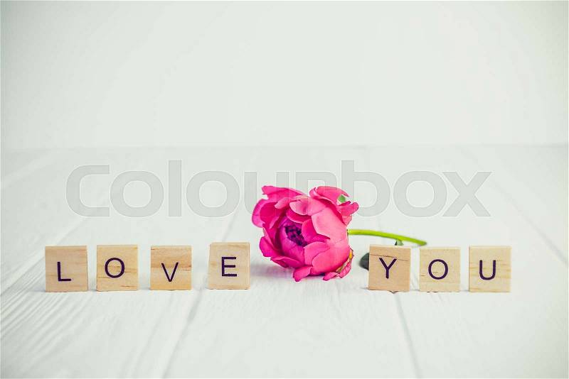 Message I love you spelled in wooden blocks with pink peony bud flower on white wooden table. Love, Valentines day background. Gift, greeting, compliment concept. ..., stock photo