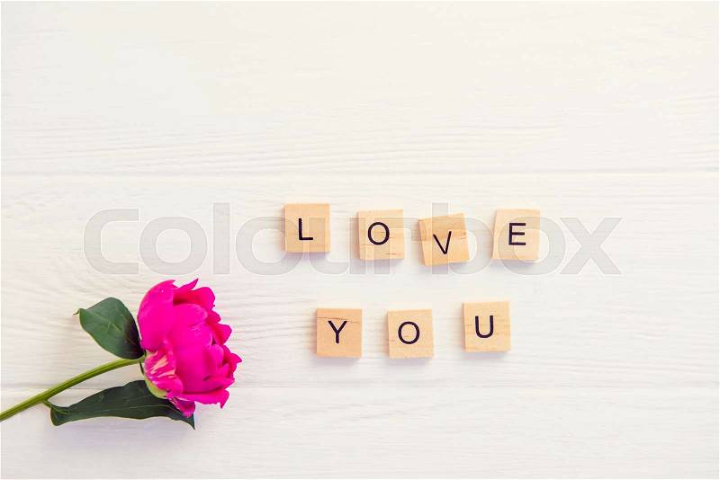 Top view Message I love you spelled in wooden blocks with purple pink peony flower on white wooden table. Love, Valentines day background. Gift, greeting, compliment ..., stock photo