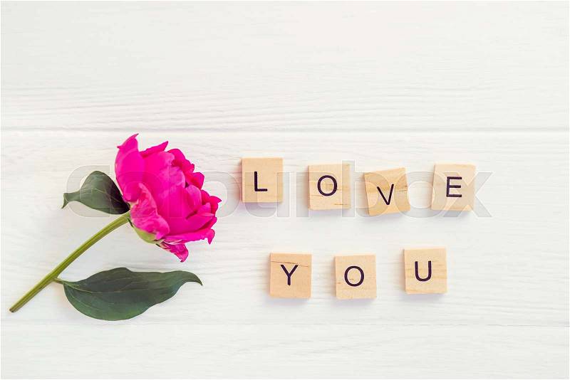 Top view Message I love you spelled in wooden blocks with purple pink peony flower on white wooden table. Love, Valentines day background. Gift, greeting, compliment ..., stock photo