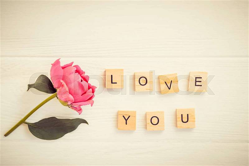 Top view Message I love you spelled in wooden blocks with pink peony flower on white wooden table. Love, Valentines day background. Gift, greeting, compliment ..., stock photo