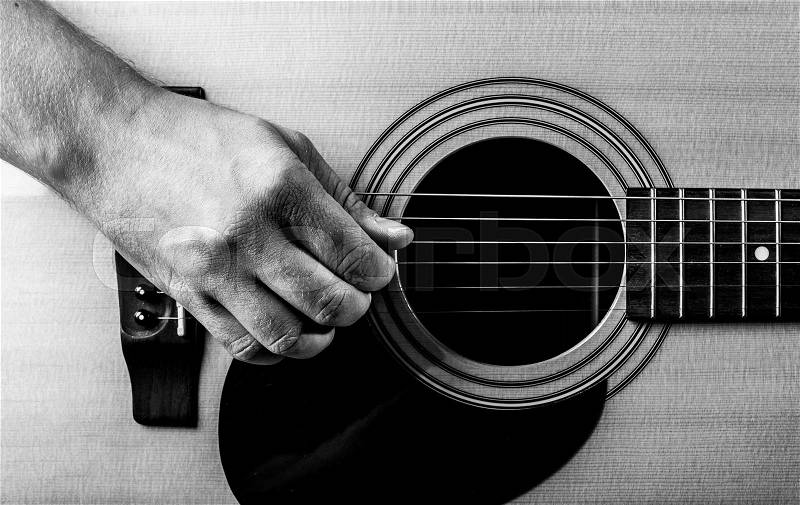 Old man\'s hand on the strings of an acoustic guitar. close-up, stock photo