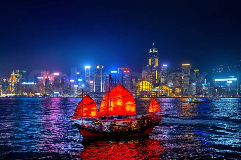 Victoria Harbour with junk ship at night in Hong Kong, stock photo