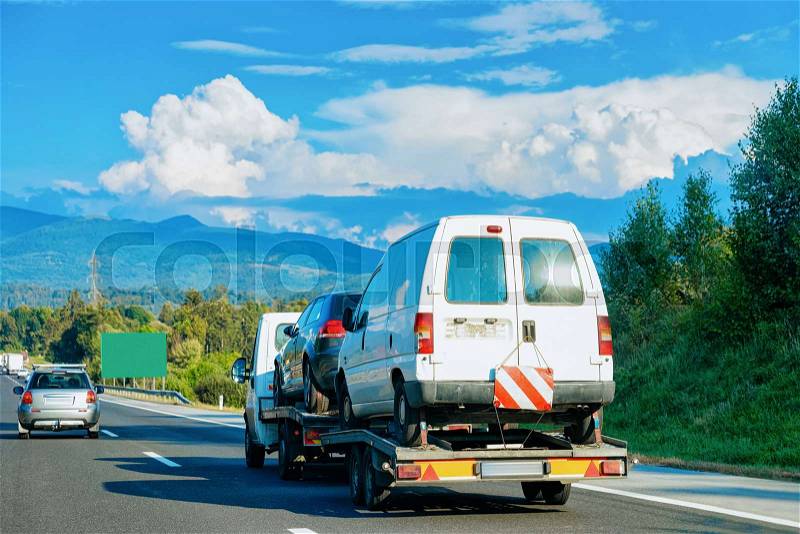 Car carrying trailer with mini vans on the asphalt road in Slovenia, stock photo