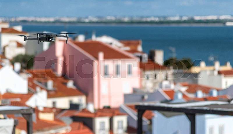 Drone flying above city buildings on a sunny day, stock photo