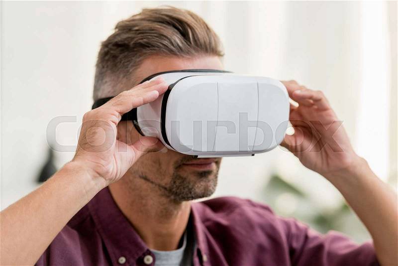 Close up view of man touching virtual reality headset, stock photo