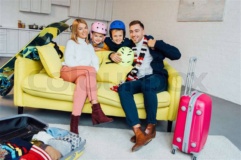 Happy family sitting on couch with ski accessories and packing for winter holidays, travel concept, stock photo