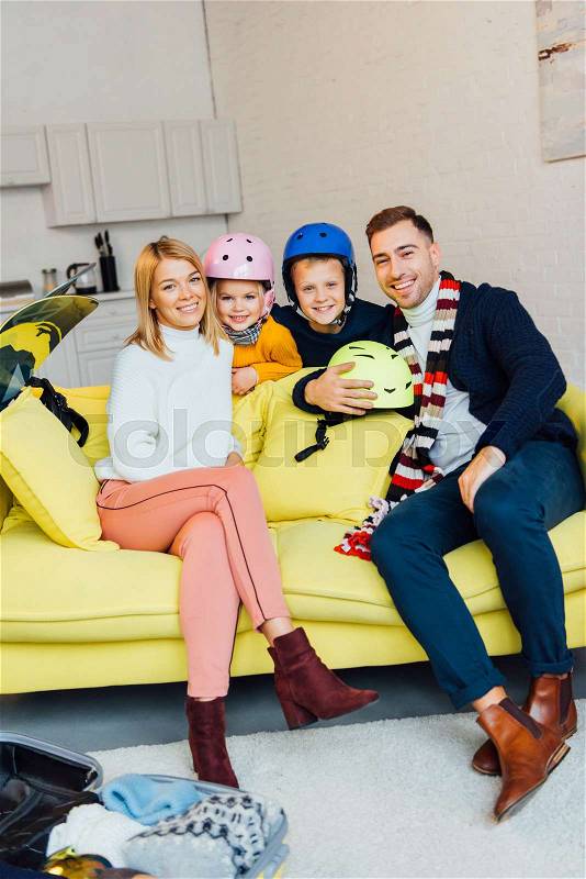 Happy family sitting on couch with ski accessories and packing for winter holidays, travel concept, stock photo