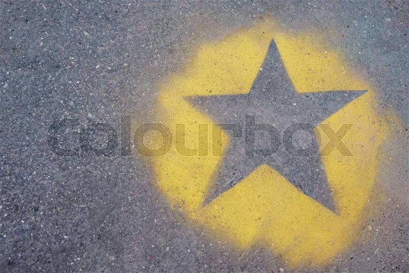 The yellow star is painted on gray asphalt, stock photo