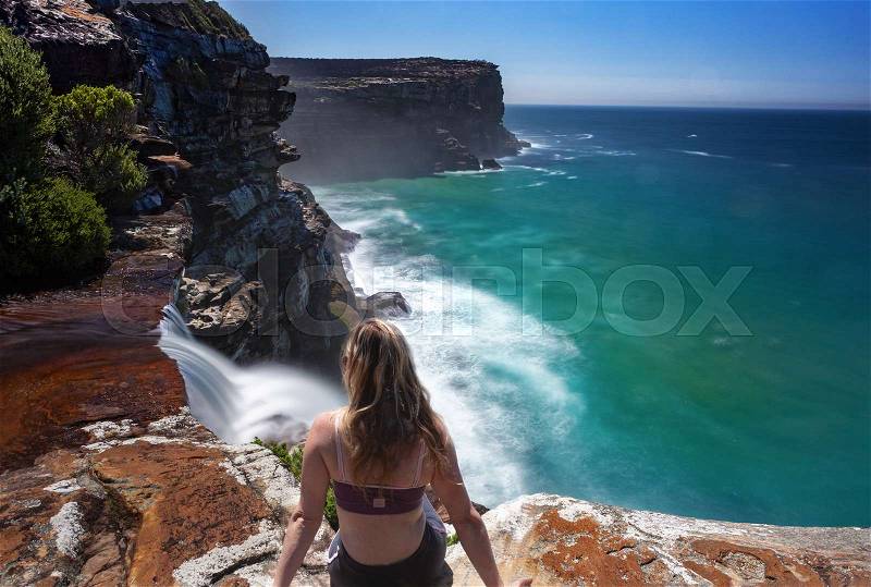 Watching waterfalls flow over sheer cliffs of the coastal headland into the ocean. Australia, stock photo