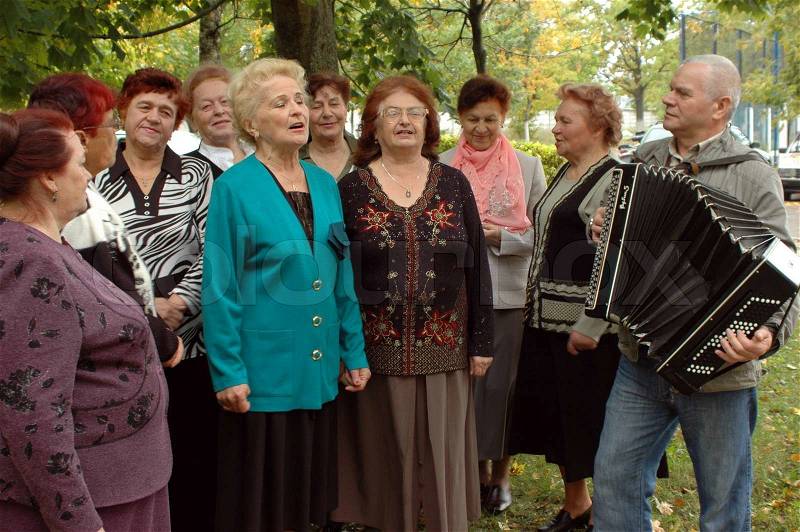Old women singing with a button accordion player, stock photo