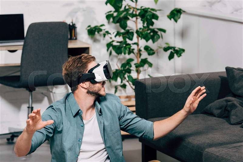 Selective focus of young man using virtual reality headset at home, stock photo