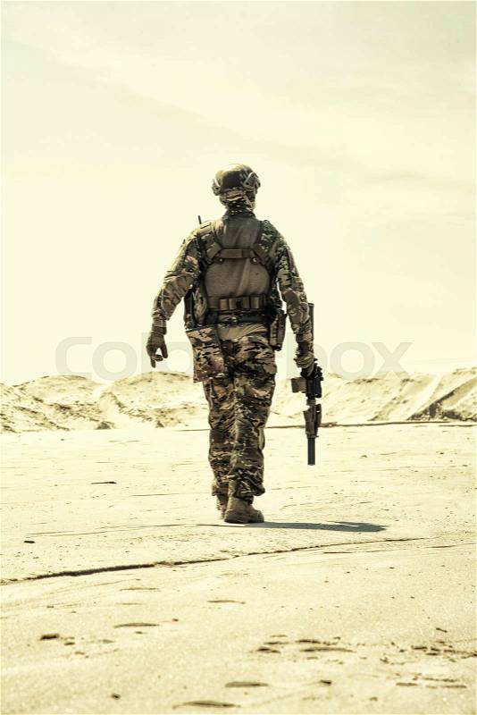 Military contractor, army infantry or rifleman in camouflage uniform and helmet patrolling territory in desert. Airsoft player with real firearm replica walking in ..., stock photo
