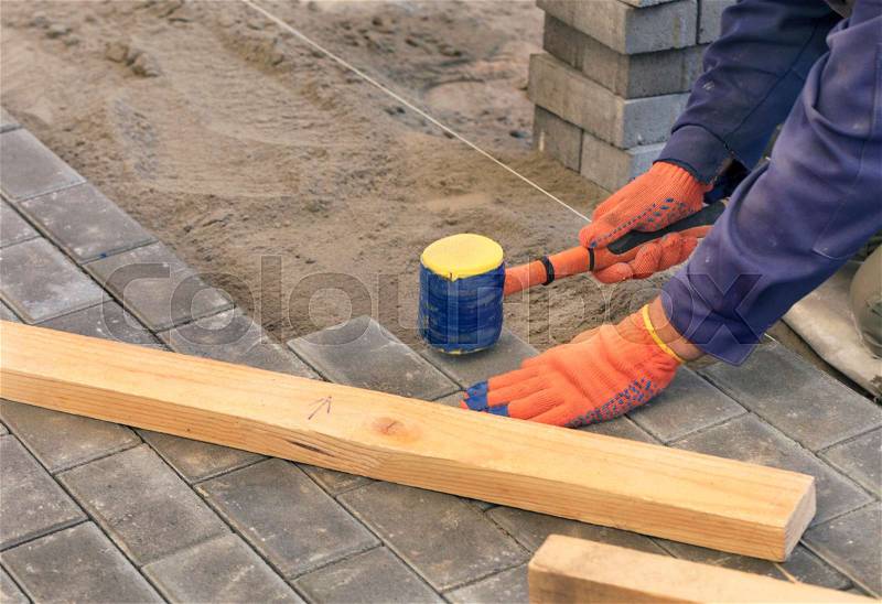 The worker lay the paving slab with special hammers, leveling it according to the level of the tensioned thread, stock photo