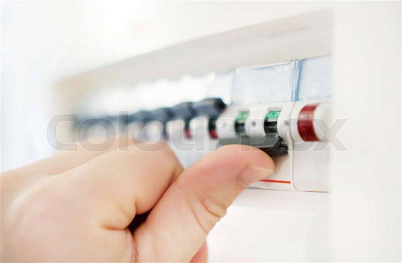 Male hand switching off fuse board, stock photo