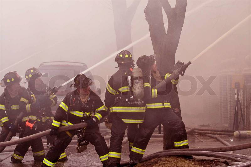 Firemen at work putting out a house fire, stock photo