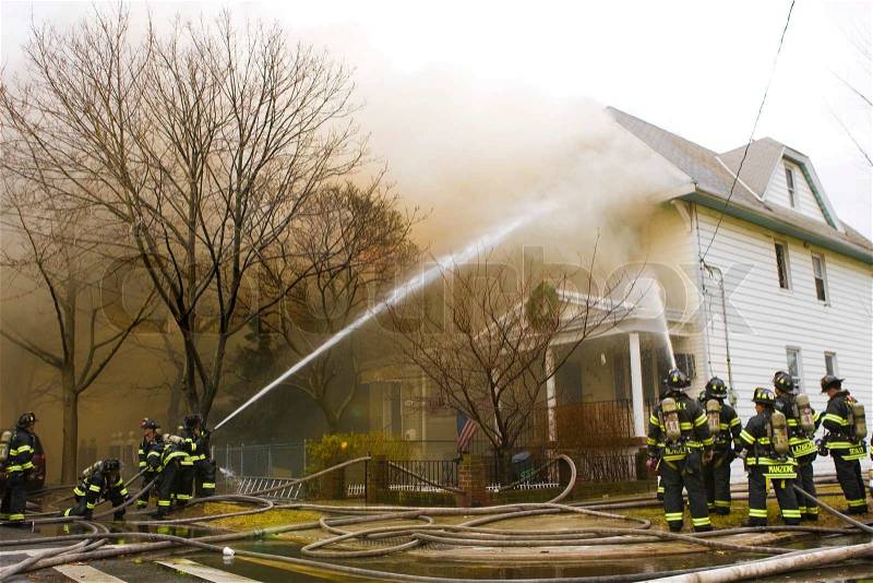 Firemen at work putting out a house fire, stock photo