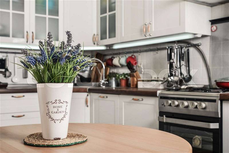 Bouquet of lavender in interior of the kitchen in Scandinavian style with white furniture and a dining table, stock photo