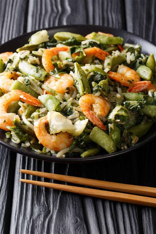 Chinese Healthy stir-fry of shrimp with spinach, soy sprouts, peas and pak choi close-up on a plate on the table. vertical, stock photo