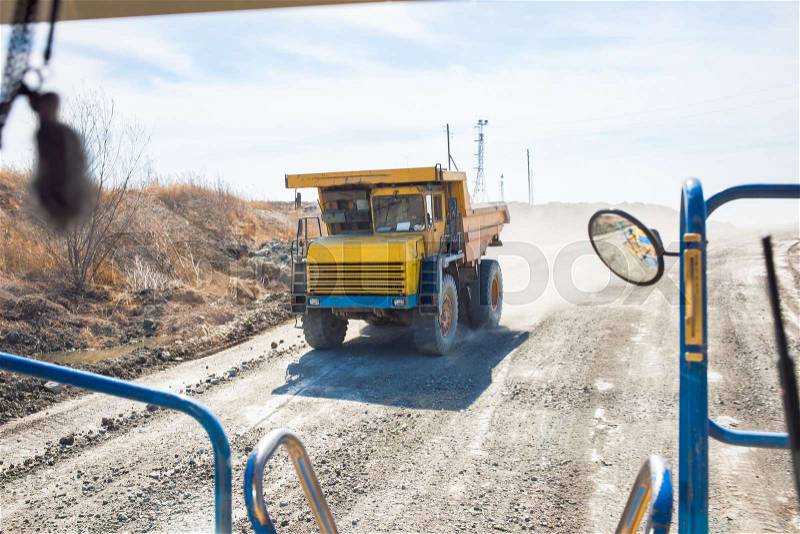 Old yellow dump truck moving in a coal mine. View from another truck, stock photo