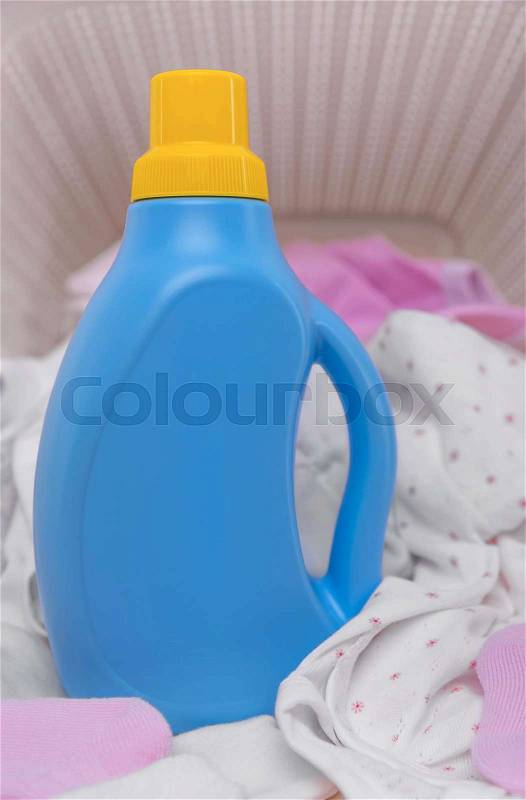 Bottle of laundry detergent in a basket of dirty baby clothes. Close-up, stock photo