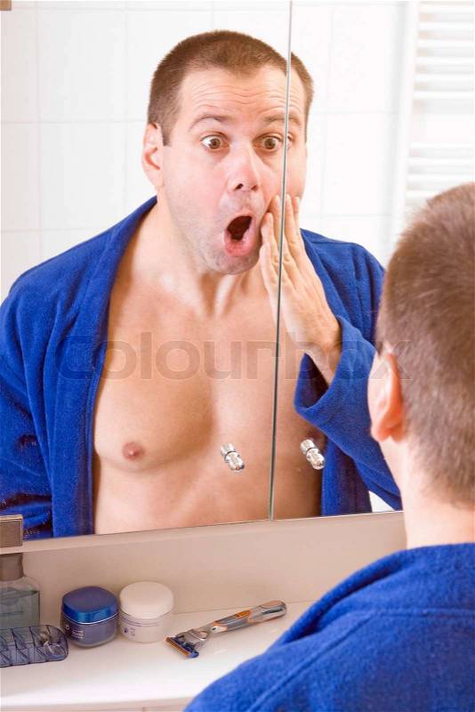 Man looks at himself in the mirror, stock photo